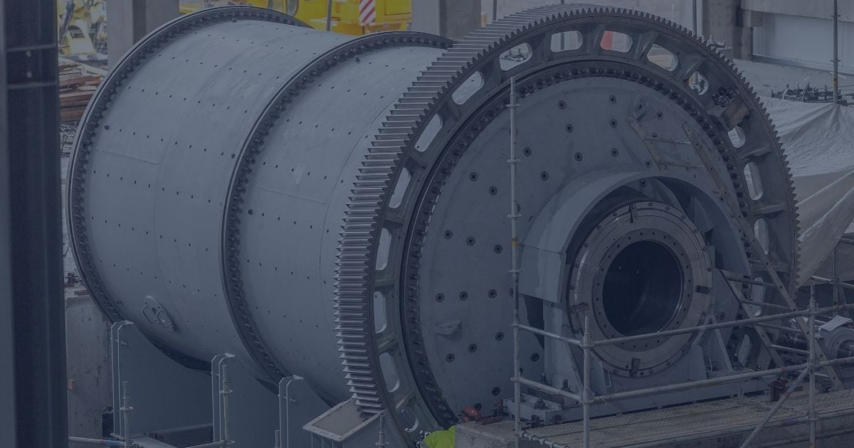Large industrial ball mill under installation at a mineral processing facility, surrounded by scaffolding and structural supports