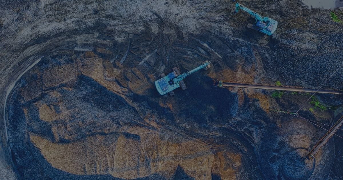 Aerial view of an open-pit mining operation with excavators and conveyor systems actively working across exposed ore and overburden layers