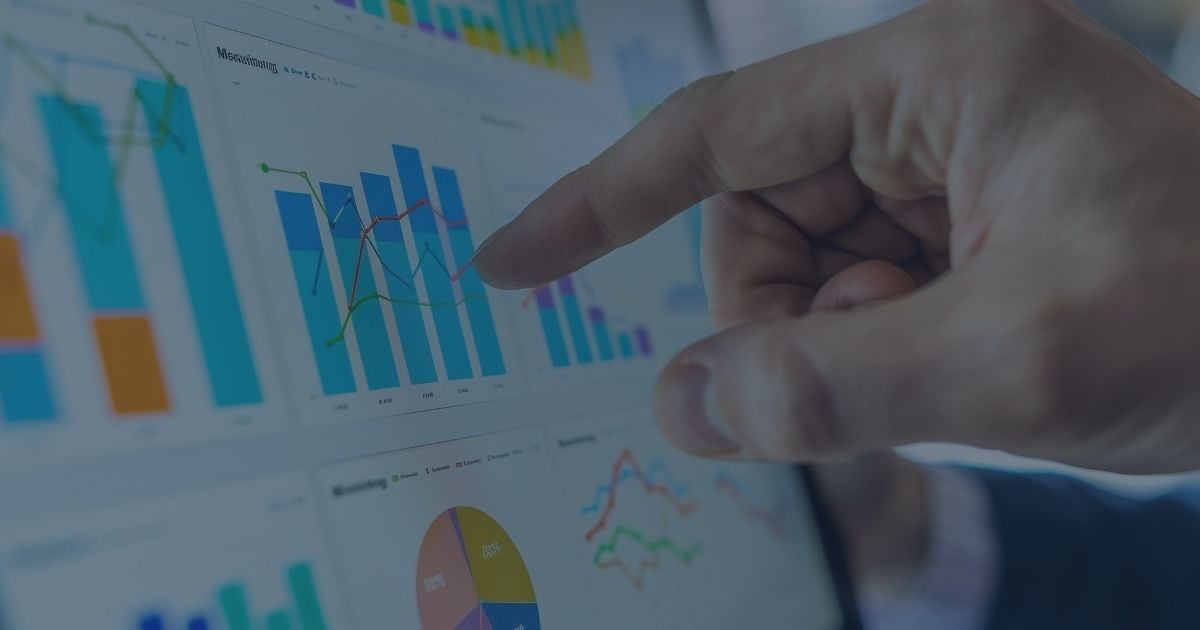 Close-up of a hand interacting with a digital dashboard displaying bar charts, line graphs, and performance metrics