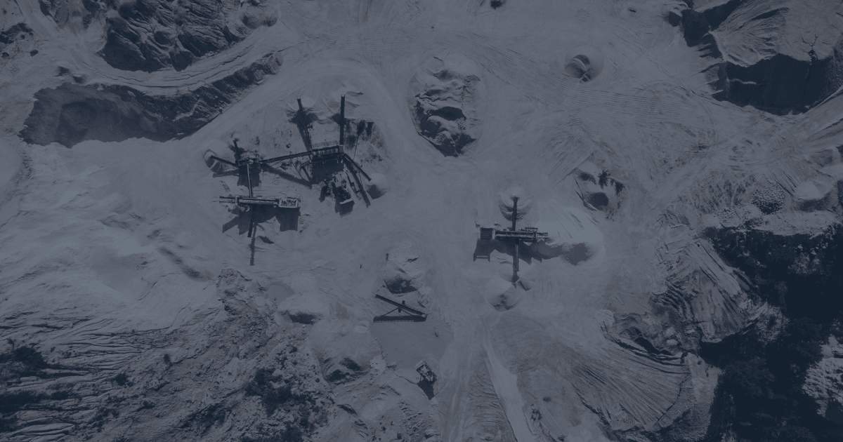 Aerial view of multiple stockpiles and conveyors at an open-pit mining site, highlighting the complexity of real-time material tracking in large-scale operations.