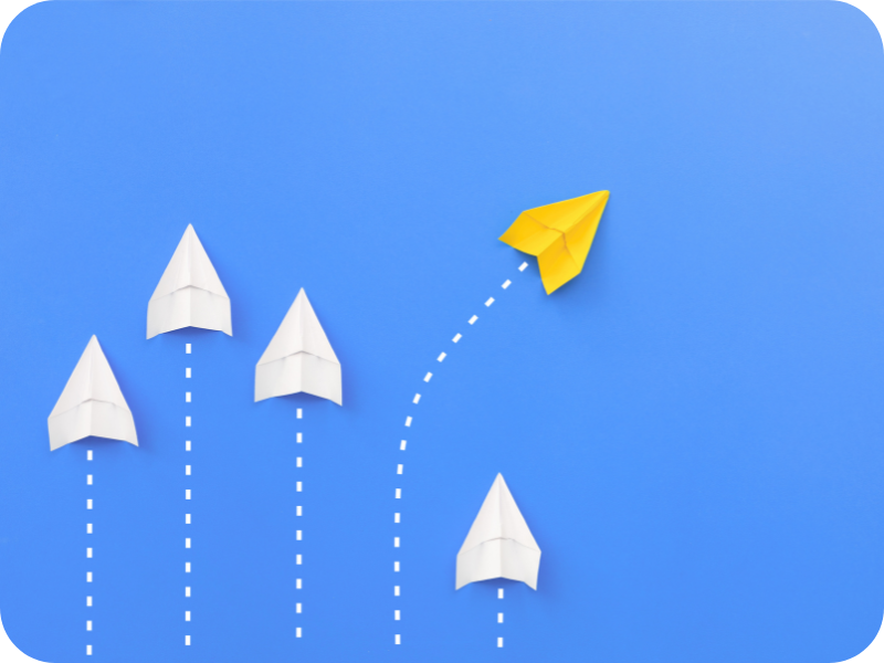 Group of white paper planes following one yellow paper plane, symbolizing strategic direction and solution differentiation